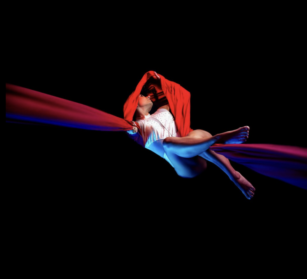 Fashion photography: figura avvolta da un tessuto rosso in movimento